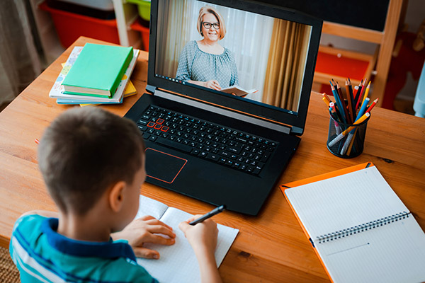 criança fazendo tarefa e assistindo videoaula