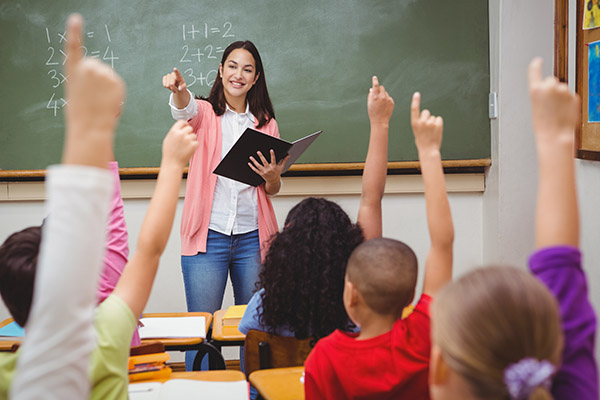 professora dentro da sala de aula e crianças com mãos levantadas